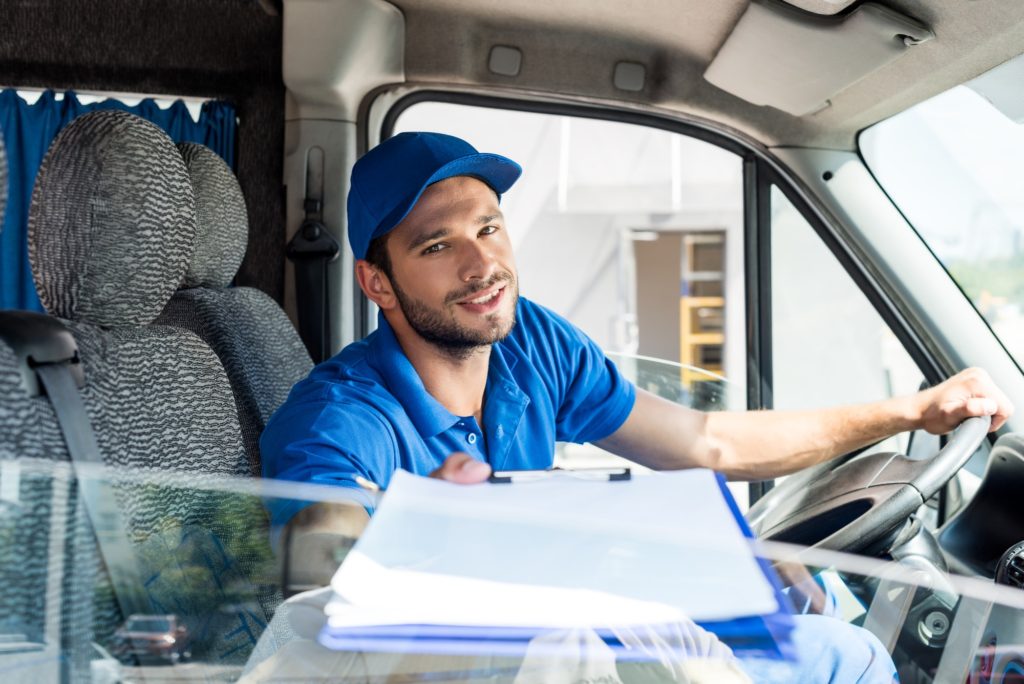 delivery man with clipboard sitting on van